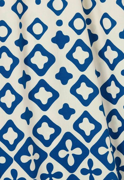 Patrón geométrico azul sobre tejido blanco con formas de diamante, cruz y círculo, con una textura suave y un diseño nítido.