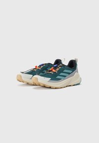 Teal and navy trail running shoes with textured fabric, rubber soles, and colorful accents. Features lacing system and padded collars.