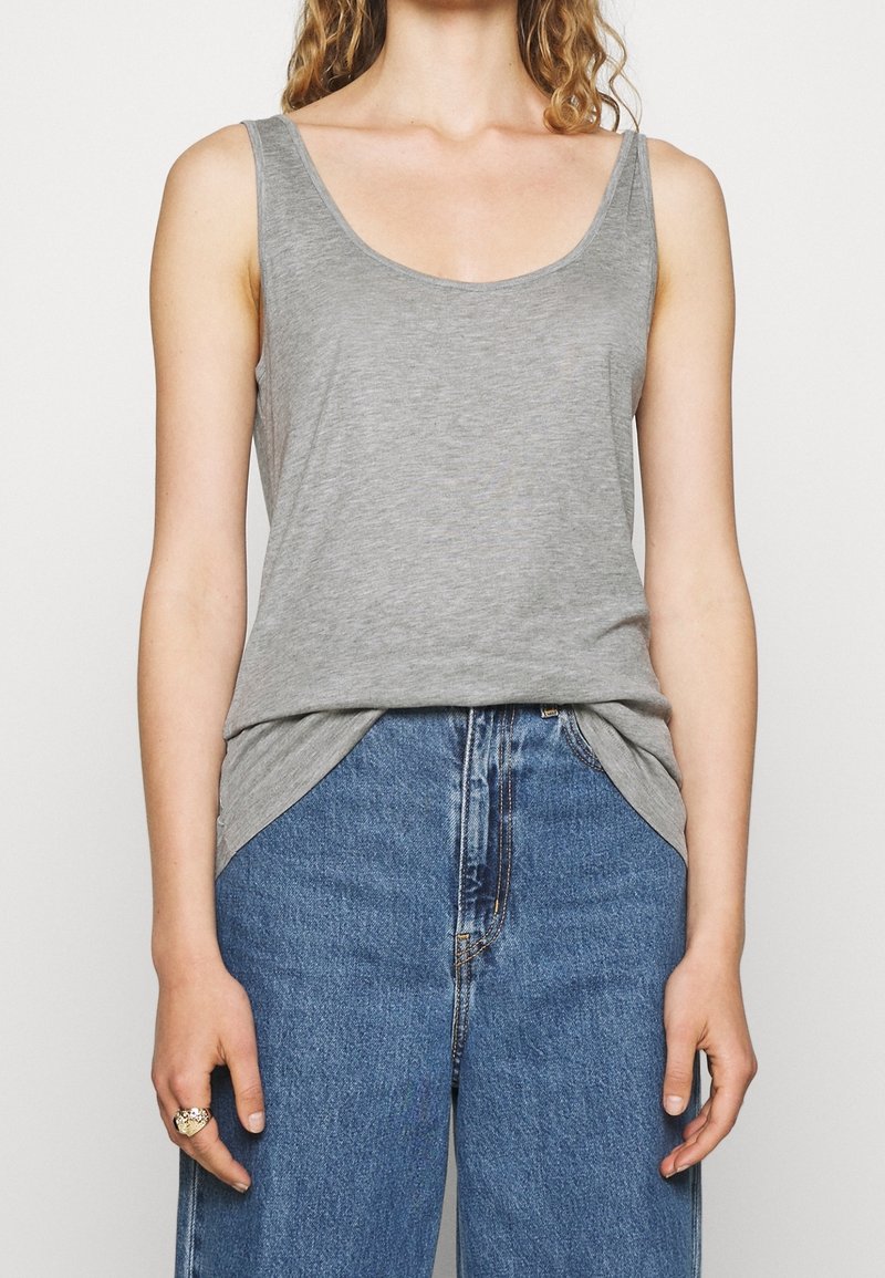Grijze mouwloze top van zachte stof, met een ronde halslijn en een losse pasvorm, gecombineerd met high-waisted blauwe spijkerbroeken.
