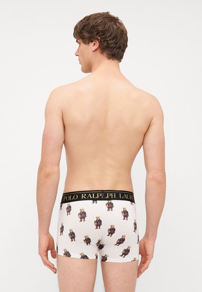 Biele boxerky s opakujúcimi sa ilustráciami medveďov v farebnom oblečení, s čiernym pásom s logom "POLO RALPH LAUREN".