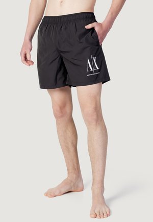Pantaloni da nuoto neri con vita elastica, tasche laterali e logo "AX" bianco sulla gamba sinistra. Realizzati in tessuto leggero e a rapida asciugatura.