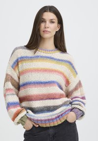 Pull en tricot avec des rayures horizontales variées en crème, rose, jaune, bleu et violet. Coupe ample avec poignets et ourlet côtelés.