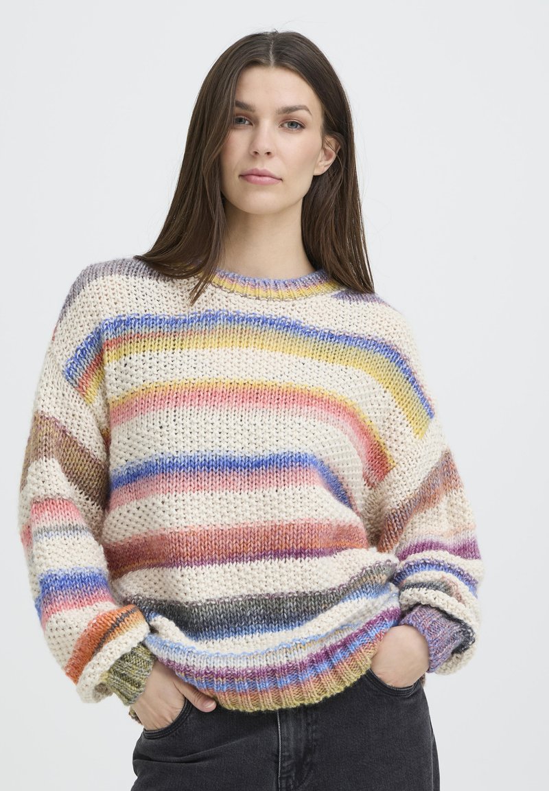 Pull en tricot avec des rayures horizontales variées en crème, rose, jaune, bleu et violet. Coupe ample avec poignets et ourlet côtelés.