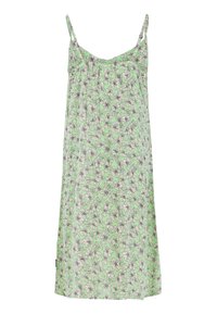 Groene bloemenjurk met dunne bandjes, met een losse pasvorm en zwartomrande witte bloemen op een lichter groene achtergrond.
