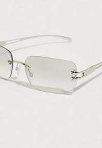 Ορθογώνια γυαλιά ηλίου με ασημένιο μεταλλικό πλαίσιο. Διαυείς φακοί, με ρυθμιζόμενα μαξιλαράκια στη μύτη και διακοσμητικό εξάρτημα στα πλαϊνά.