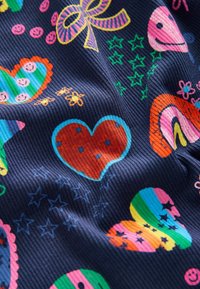 Tessuto colorato con diversi motivi, tra cui cuori, stelle e facce sorridenti, su uno sfondo blu scuro con texture a righe.
