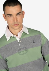 Kraagloze rugbyshirt in grijs en groene strepen, met een roze binnenkraag, geborduurde accenten en een textuurstof.