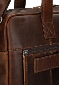 Brown leather messenger bag with a smooth texture, zippered pocket, and contrasting stitching. Features durable hardware and a structured design.