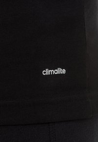 Czarny t-shirt o miękkiej fakturze, z białym napisem „climalite” na dolnym boku. Prosty design bez wzorów i dodatków.