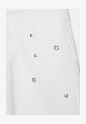 Hvidt stof med fem sølvfarvede metal-øjer i forskellige størrelser tilfældigt arrangeret nær en søm og lommeomrids.