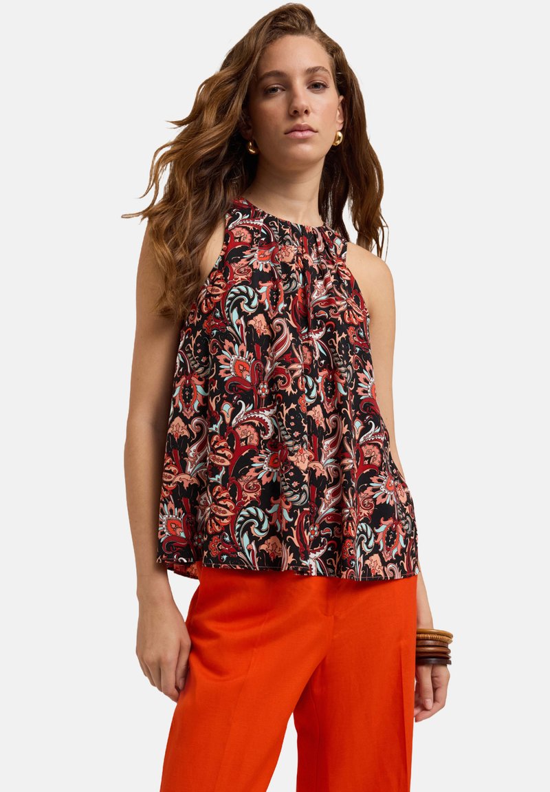 Top negru fără mâneci cu imprimeu floral colorat, decolteu strâns și croială lejeră, purtat cu pantaloni portocalii strălucitori.