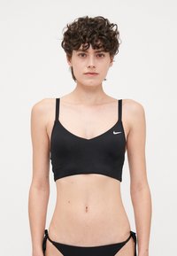 Black bikini top with thin straps, V neckline, and logo detail. Smooth, stretchy fabric with a fitted design. Simple and minimalistic style.