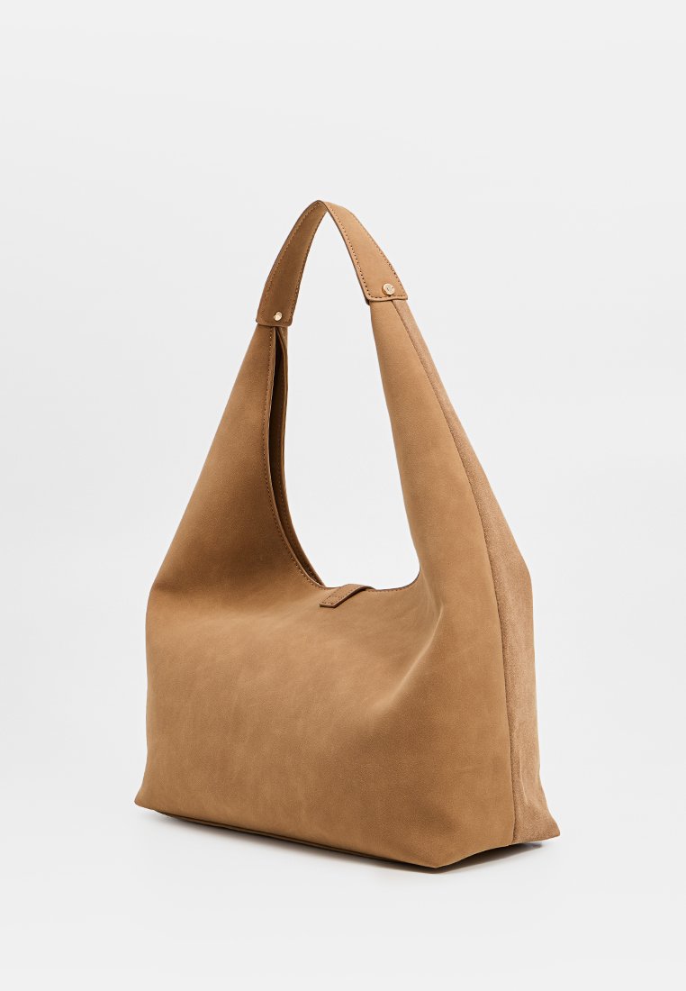 Hellbraune Hobo-Tasche mit einem breiten, einzelnen Trageriemen, glatter Textur und einem schlichten, offenen Design. Hat eine minimalistische Silhouette.