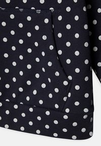 Marinblå sweatshirt med stora vita prickar, med en framficka och ribbad nederkant. Tillverkad av mjukt, texturerat bomullsmaterial.