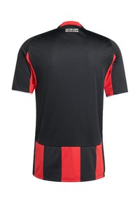 Maillot de sport à manches courtes noir et rouge avec des rayures verticales en bas et le texte "NUR EINE STADT. NUR EIN VEREIN." dans le dos.
