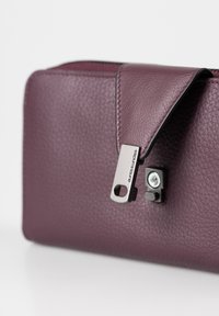 Paarse leren pochette met een gerimpelde textuur, voorzien van een klepverclosure en een metalen ritssluiting met merkdetail.