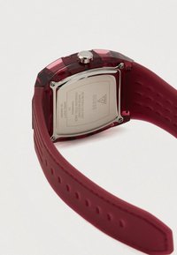 Rødt ur med et rektangulært, glansfuldt plastetui, rustfrit stålhætte og tekstureret gummirem med en række små huller.