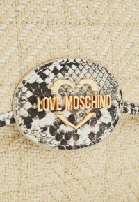Punottu beige-käsilaukku, jossa on pyöreä musta-valkoinen käärmeennahkakuosiset solki ja kultasävyinen "LOVE MOSCHINO" -teksti keskellä.