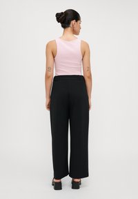 Top de manga curta rosa e calças largas pretas; tecido suave; cintura elástica; cores sólidas; design simples; vista traseira.