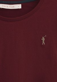 Bordeauxfarbene Baumwoll-T-Shirt mit rundem Halsausschnitt und einem in Creme gestickten Golfer-Logo auf der linken Seite. Klassische Passform mit weicher Textur.