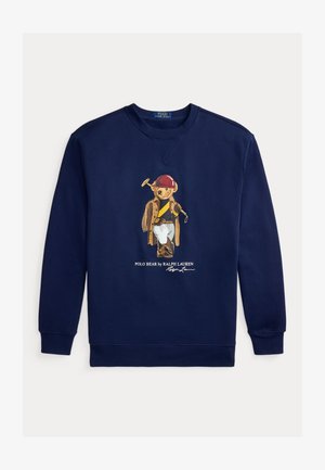 Tumesinist värvi dressipluus, millel on graafika Polo Kallist, kes on riietatud ratsutamisvarustusse, sealhulgas kiivri, mantli, saapad ja hoiab polomalleti.