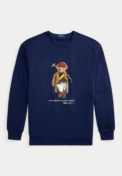 Temno modra jopa s potiskom Polo medveda oblečenega v jahalno opremo, vključno s čelado, plaščem, škornji in držeč polinski lopar.