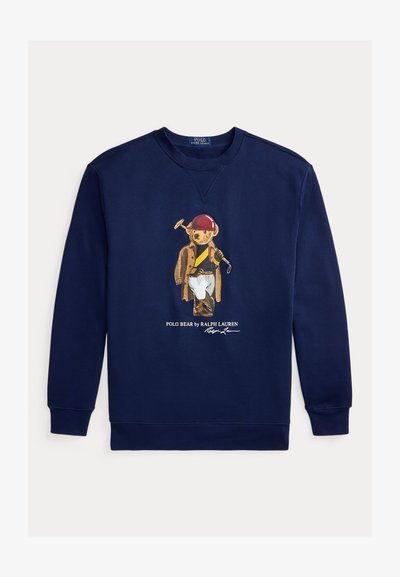 Temno modra jopa s potiskom Polo medveda oblečenega v jahalno opremo, vključno s čelado, plaščem, škornji in držeč polinski lopar.