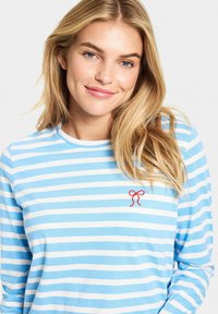 Lichtblauw en wit gestreept long-sleeve shirt gemaakt van zachte stof; heeft een rode geborduurde strikdetail op de linkerborst.