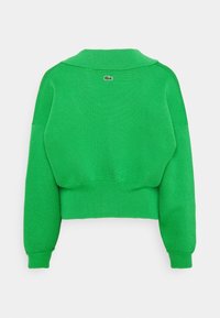 Pullover verde lavorato a maglia con design corto, maniche ampie e polsini a coste. Il dettaglio del colletto sul retro presenta un piccolo accento con logo.