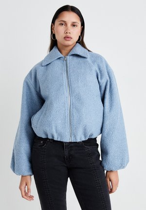 Chaqueta bomber de forro polar en azul claro, con cierre de cremallera, amplio cuello y mangas voluminosas. Tejido texturizado, cinturilla acanalada.