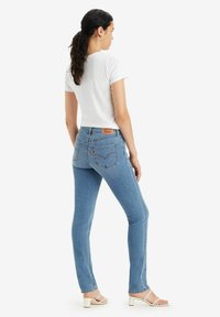 Jeans ajustados de denim en azul claro, con una cintura de altura media, dos bolsillos traseros y un parche de logo de cuero en la cintura.