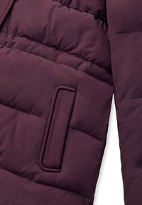 Primo piano di una manica di giacca trapuntata di colore viola scuro e tasca frontale imbottita con dettaglio a pattina verticale.