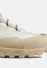 Beżowe buty na zewnątrz z teksturowaną cholewką i gładką gumową podeszwą. Posiadają wzmocniony czubek i wzorzyste sznurowadła zapewniające pewne dopasowanie.