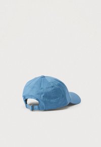 Plava pamučna bejzbol kapa s zakrivljenim vizorom, podesivim remenom straga i detaljima šavova duž šavova. Teksturirana tkanina.