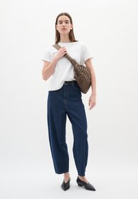 T-shirt bianca in cotone, pantaloni a vita alta in denim blu scuro a gamba larga, borsa a spalla trapuntata marrone scuro e mule con tacco neri.