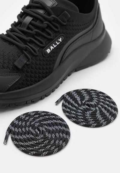 Sneaker nera realizzata in maglia a maglia con tomaia testurizzata, lacci piatti e suola in gomma. Include due paia di lacci a spirale in bianco e nero.