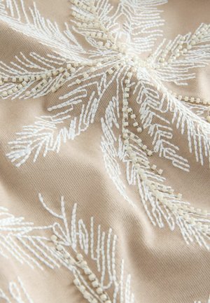 Broderad textil med en beige bakgrund och vita bladmönster samt små, texturerade pärlor som omger designen.