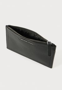 Must tumed nahkainel zip-kott, millel on tekstureeritud välimus, hõbedane tõmblukk ja logo detail esipoolses osas. Sisemus on vooderdatud kangaga. Kompaktne disain.