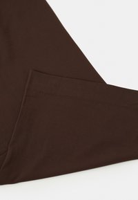 Un tissu plié marron foncé avec une texture lisse sur une surface blanche.