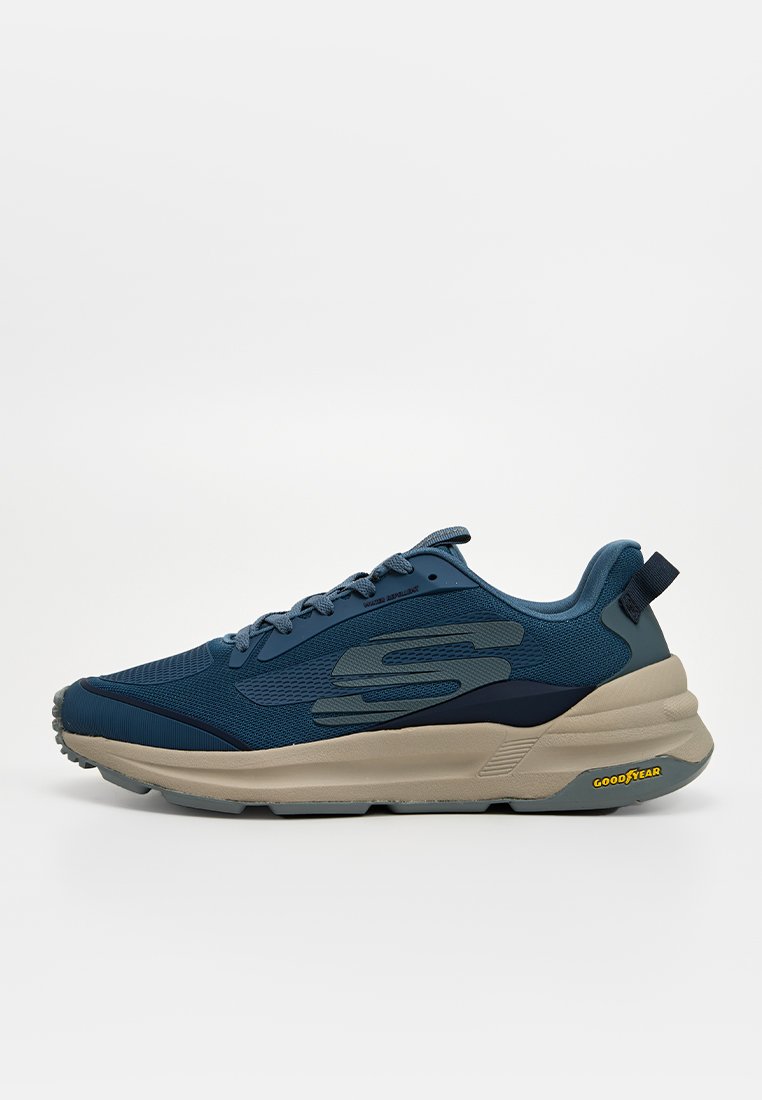 Scarpa sportiva blu con tomaia in rete e dettagli sintetici. Presenta una suola spessa beige e un tab sul tallone nero con il marchio "Goodyear".