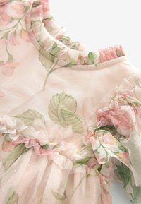 Robe fleurie en tissu léger et transparent rose clair avec un col et des manches à volants. Présente des fleurs roses et des feuilles vertes. Accents dorés subtils.