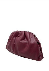 Burgundská kožená kabelka s nařaseným designem, hladkým povrchem a jemným leskem. Na jedné straně obsahuje kulatý kovový akcent.