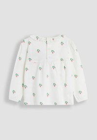 Blusa bianca a maniche lunghe con colletto a balze, caratterizzata da un motivo di fragole nei toni del rosa e del verde, e chiusura a bottone sul retro.