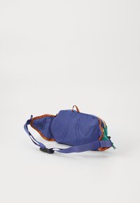 Borsa cintura in tessuto viola con dettagli marroni, chiusura con zip e tracolla regolabile. I lati texture e un dettaglio a cappotta verde sono visibili.