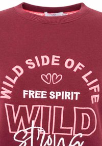 Bordeaux-rotes Sweatshirt mit besticktem Text "WILD SIDE OF LIFE FREE SPIRIT WILD STRONG" in Pink und Weiß, rundes Design, gerippter Kragen.