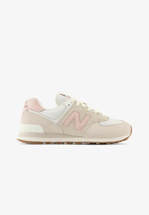 Sneaker New Balance beige e bianca con logo e dettagli rosa, lacci bianchi e suola in gomma color caramello, profilo laterale su sfondo bianco.
