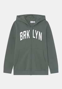 Sudadera verde con cremallera y la palabra "BRKLYN" impresa en blanco en el pecho. Cuenta con capucha y bolsillos frontales. Tejido suave, puños de canalé.