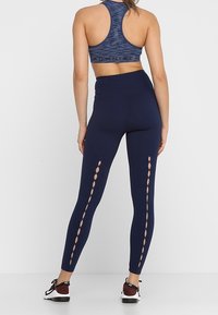 Marinblå cykelbyxor med utskärningar längs sidorna, tillverkade av stretchigt material. Kombineras med en matchande sport-bh med racerback.