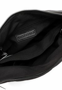 Black fabric bag interior with multiple compartments, zipper closure, and a leather tag embossed with "EMILY & NOAH." Smooth texture.