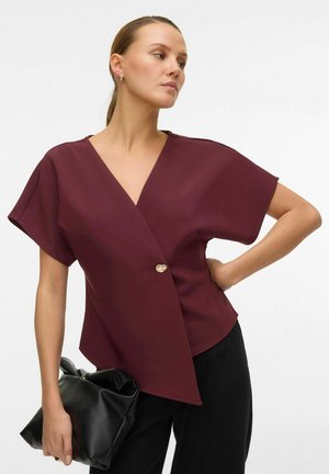 Burgundia värvi ümberlõige särk lühikeste varrukatega, millel on kuldne nööbikaunistus ja mis on kombineeritud musta nahk-kotiga. Siledad tekstuur ja voodriga lõige.